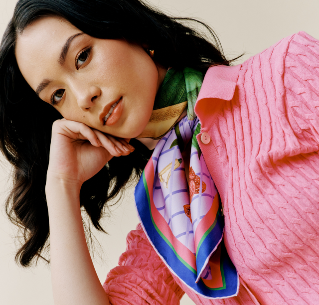 Model wears scarf styled in a cowgirl knot and holds an end of the scarf