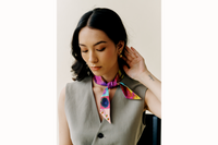 Model looks away from the camera and wears a grey vest with scarf tied around her neck