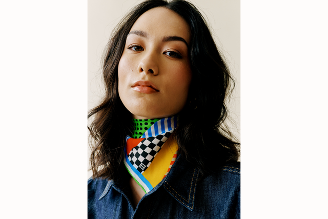 Image of female model wearing the scarf tied as a bandana with scarf draping over front of the base of her neck. 