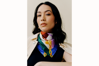 female model wears scarf tied around her neck with a black tank and off white jacket