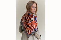 Image of the back female model looking off to the right while wearing the scarf draped over the shoulder of a neutral trench coat.