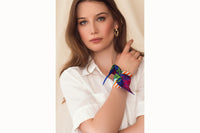 Image of female model wearing the scarf wrapped around her wrist and tied like a silk bracelet. Model is wearing a white button down shirt.