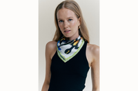 Image of female model wearing the scarf tied as a bandana around her neck. She is also wearing a black tank top.