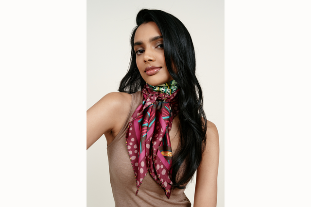 Image of female model wearing the scarf wrapped around her neck and tied in the front so that the tail ends drape down her brown tank top.