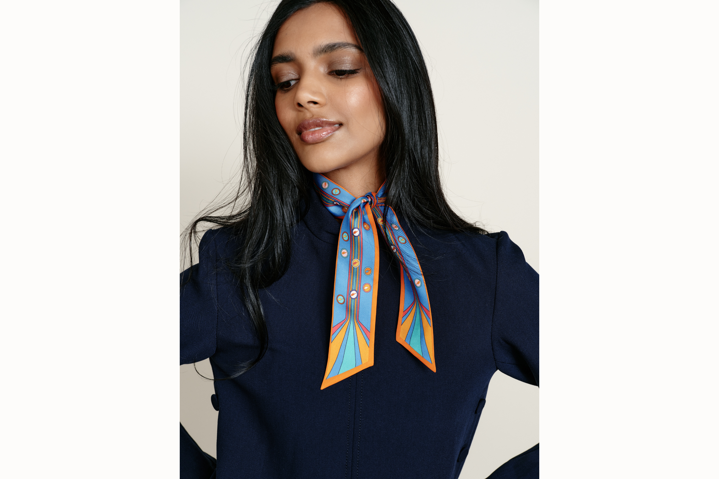 Image of a female model wearing the scarf wrapped around her neck with tail ends of the scarf draping onto her chest. Model is wearing a navy coord ensemble.