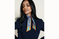 Image of a female model wearing the scarf wrapped around her neck with tail ends of the scarf draping onto her chest. Model is wearing a navy coord ensemble.