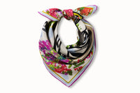 Image of a rolled and knotted 100% silk square scarf featuring a motif of three black female stick figures dressed for a night out and standing in front of the hotel entrance surrounded by urns and floral arches. The elements are in various shades of pink, green, soft red and baby blue splashed across a white background.