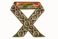 Flatlay image of 100% silk ribbon style scarf, 2” wide by 32” long folded into a cross fold shape so both sides of the scarf are seen. Featuring an abstract elephant motif and a pattern inspired by a traditional African painting composed of orange, army green, and hints of blue.