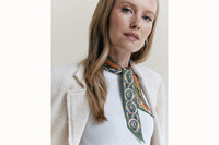 Female model wearing scarf around her neck with a cream tweed blazer and white tank.