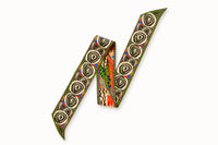 Flatlay image of 100% silk ribbon style scarf, 2” wide by 32” long folded into a zig-zag shape so both sides of the scarf are seen. Featuring an abstract elephant motif and a pattern inspired by a traditional African painting composed of orange, army green, and hints of blue.