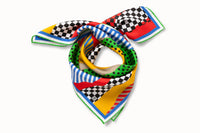 Rolled image of 100% silk square scarf featuring a high energy collage of blocks of color interrupted by lines, polka dots and checkers. Colors include black, white, stop sign red, kelly green, bright yellow and azure blue.