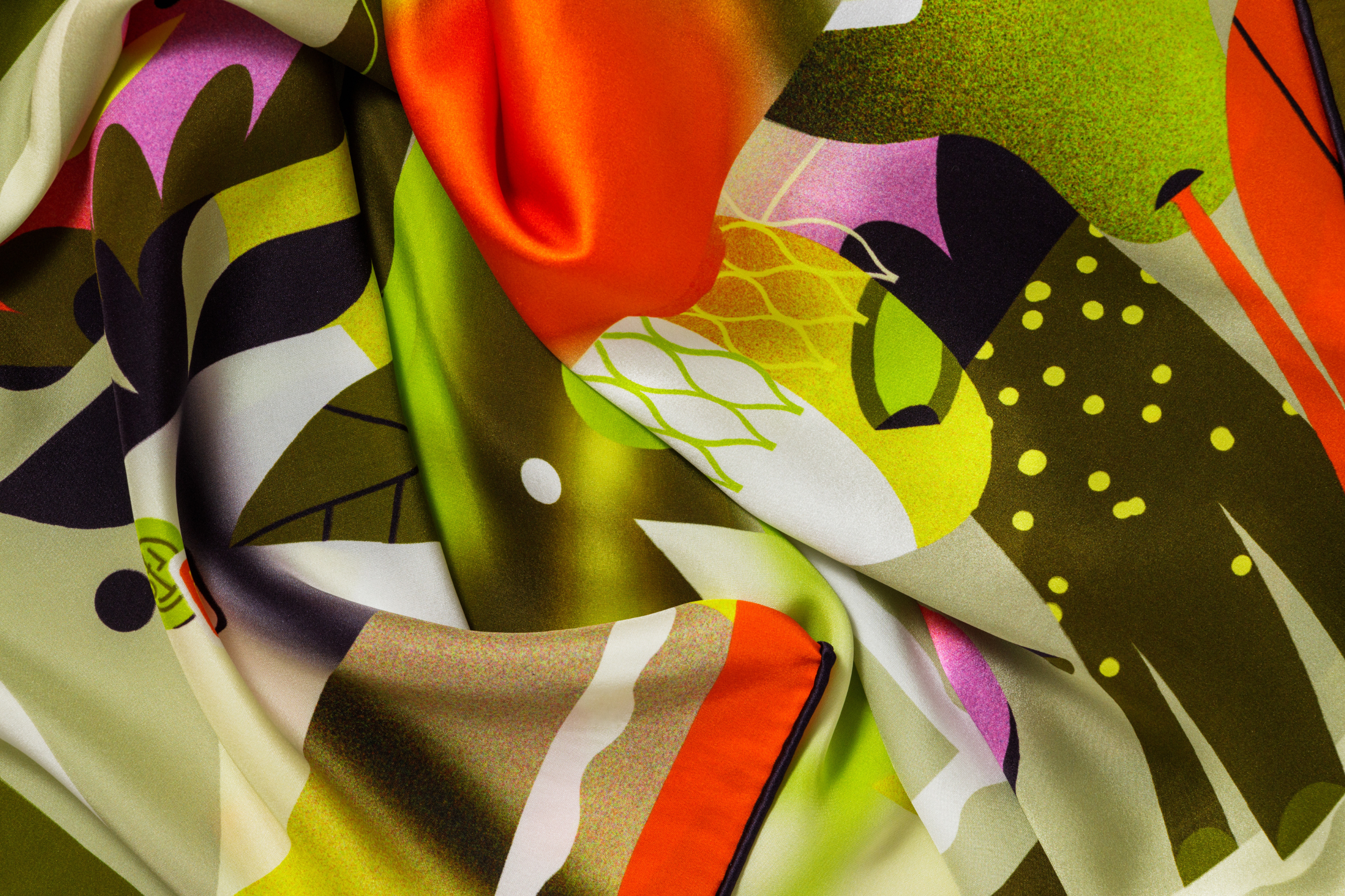 Close-up image of 100% silk square scarf featuring a collage of fruits, vegetables, and flowers in luscious shades of green and yellow, with pops of orange and pink throughout, illustrating the lightly ridged texture of the silk twill along with the rich color tones and luminous nature of the silk scarf. 