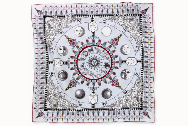 Flat lay image of 100% silk square scarf featuring a black line illustration motif of zodiac, moon phases + the natural elements against a white background. Merlot borders around the scarves' edges.