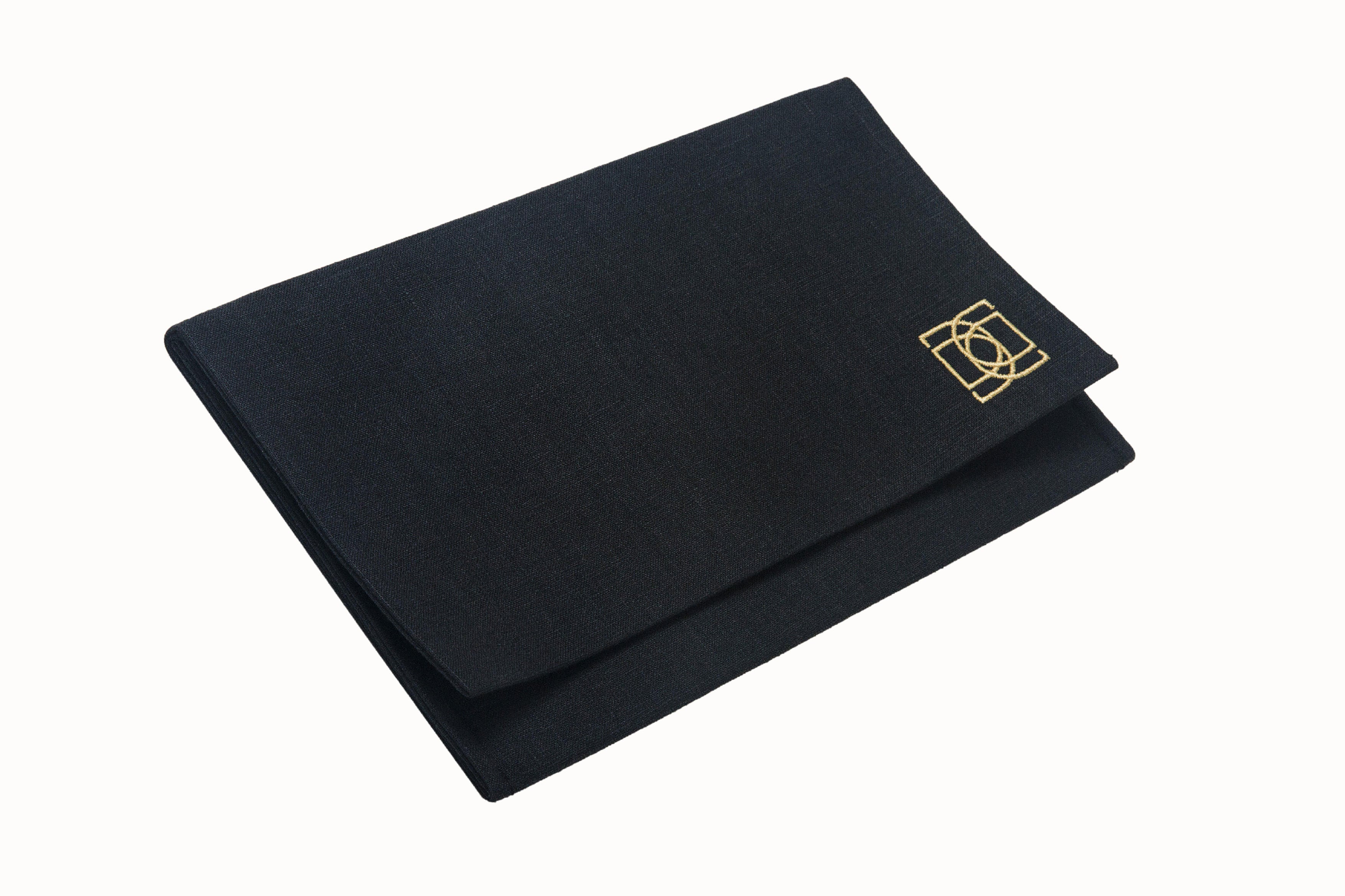 Image of our DESEDA scarf packaging. A rectangular envelope-style pouch made of 100% black linen and embroidered with our DESEDA Logo in a soft gold tone. Used for scarf storage and packaging for travel