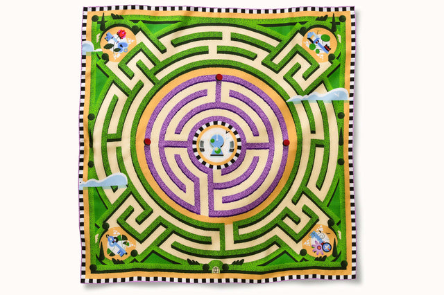 Flatlay image of 100% silk square scarf featuring a motif of a garden labyrinth with green hedges and purple lavender elements on a warm cream background. Also features a blue key and floral detail in each of the four corners of the scarf as well as a black and white checker border around the edges.