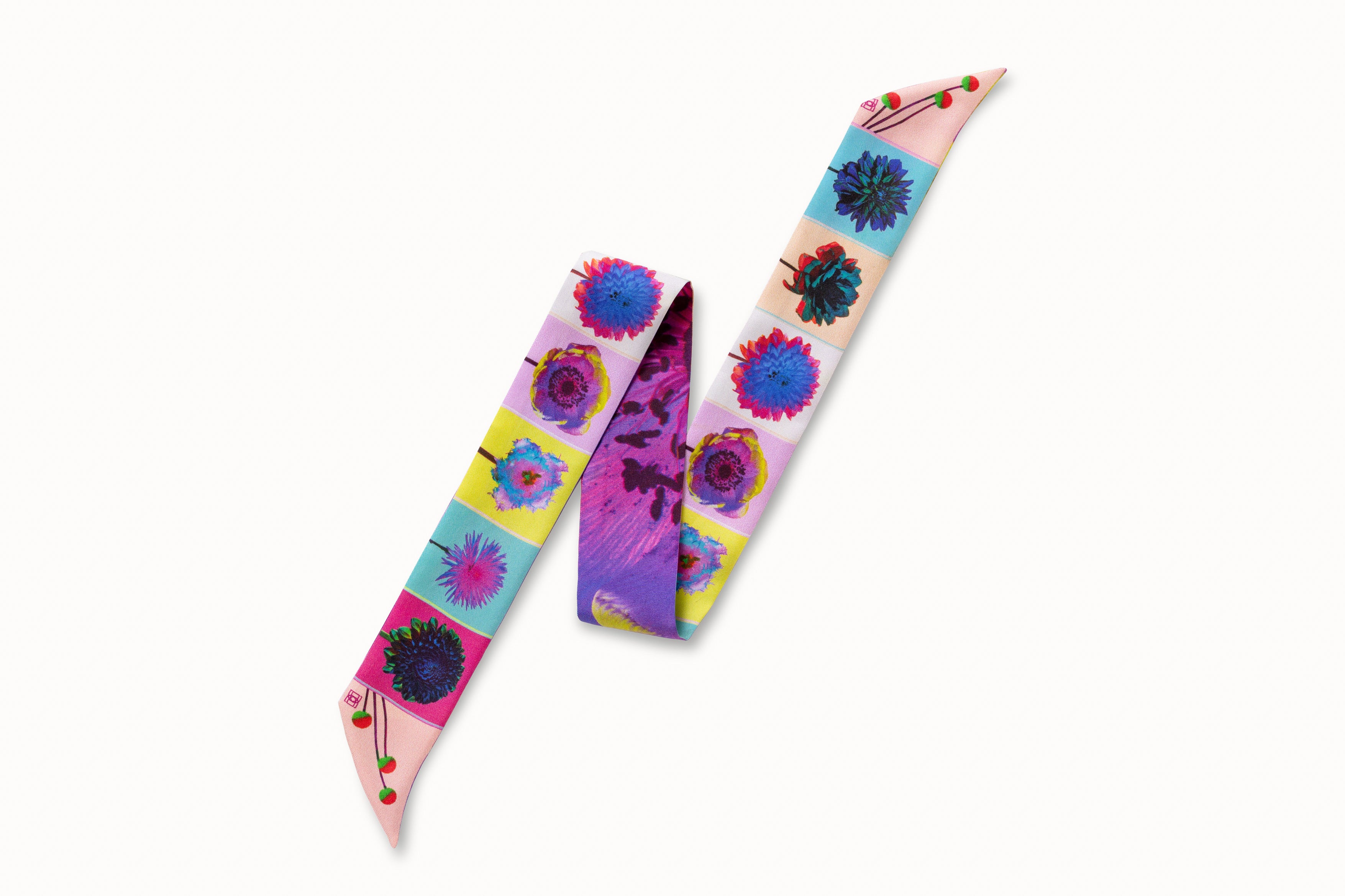 Flatlay image of 100% silk ribbon style scarf, 2” wide by 32” long, folded into a zig zag shape so both sides of the scarf are seen. Design features a series of brightly colored flowers in shades of pink, blue, green and yellow and an abstract close-up of a purple and yellow flower petal on the other.