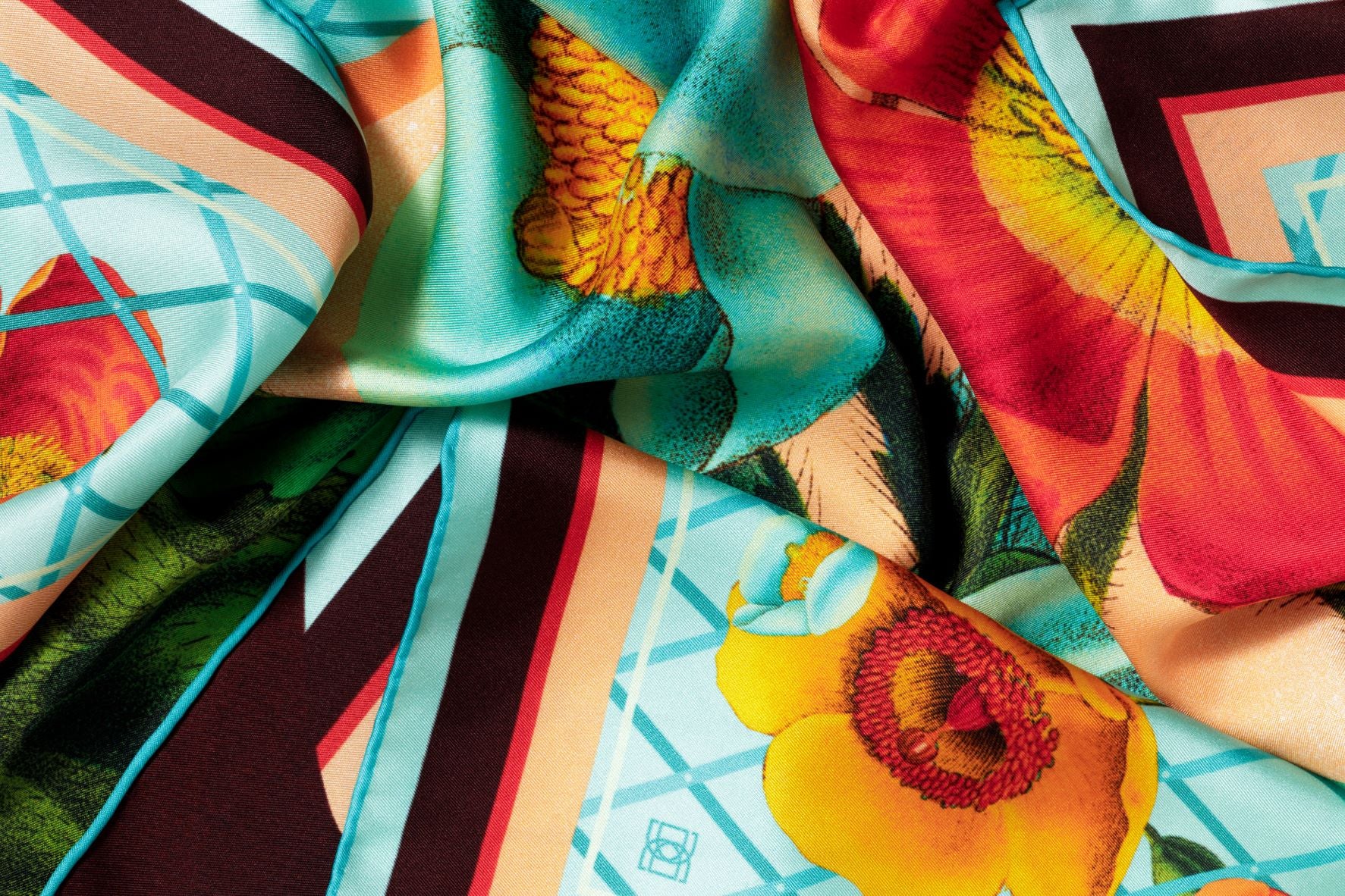 Close-up image of 100% silk square scarf featuring a vivid floral collage of bright turquoise, coral and orange. illustrates the lightly ridged texture of the silk twill along with the rich color tones and luminous nature of the silk scarf. 