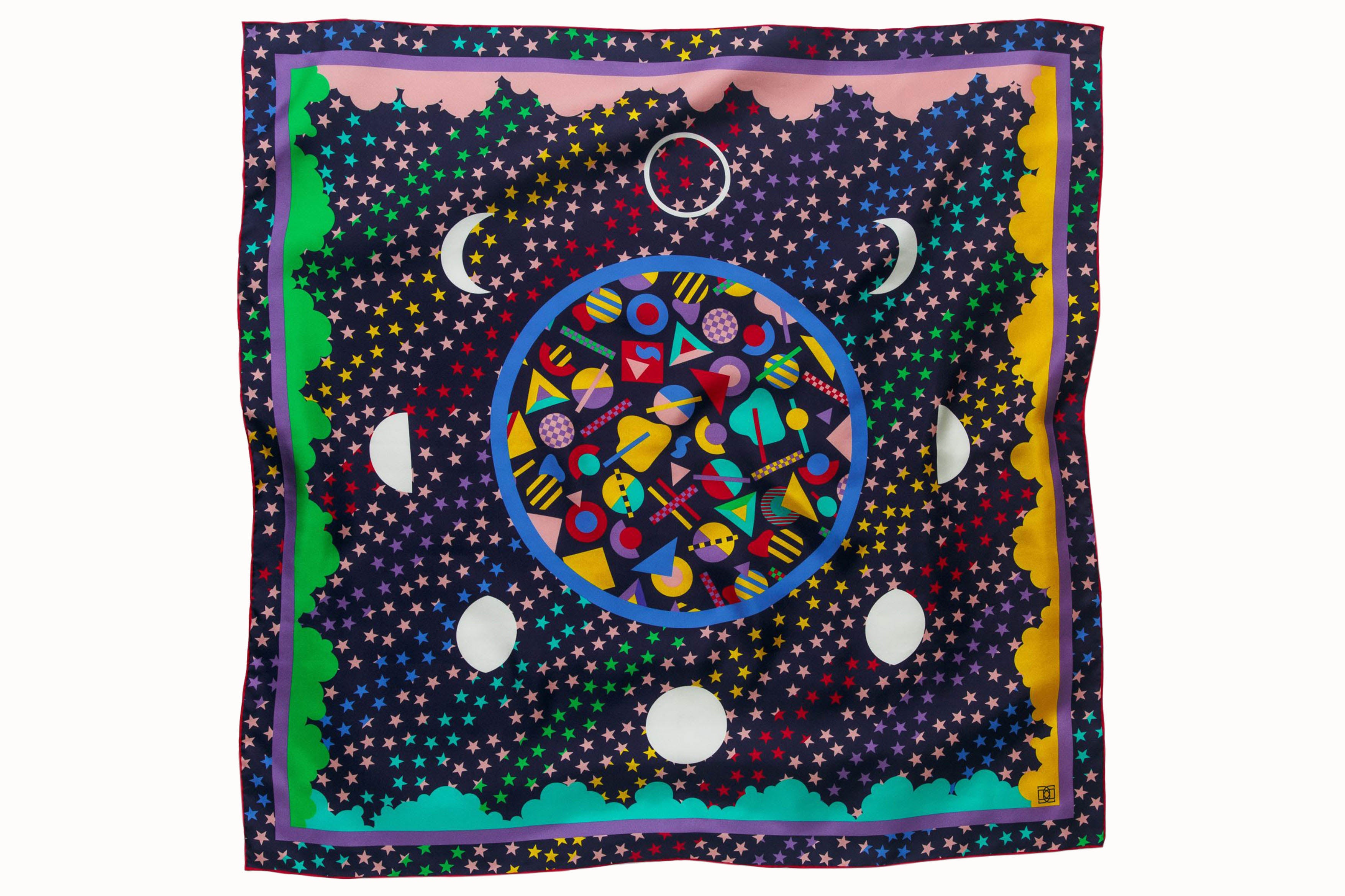 Flatlay image of 100% silk square scarf featuring a motif of brightly colored stars, clouds and white moon phases throughout. The center features colorful geometric shapes as a compliment to the celestial theme.