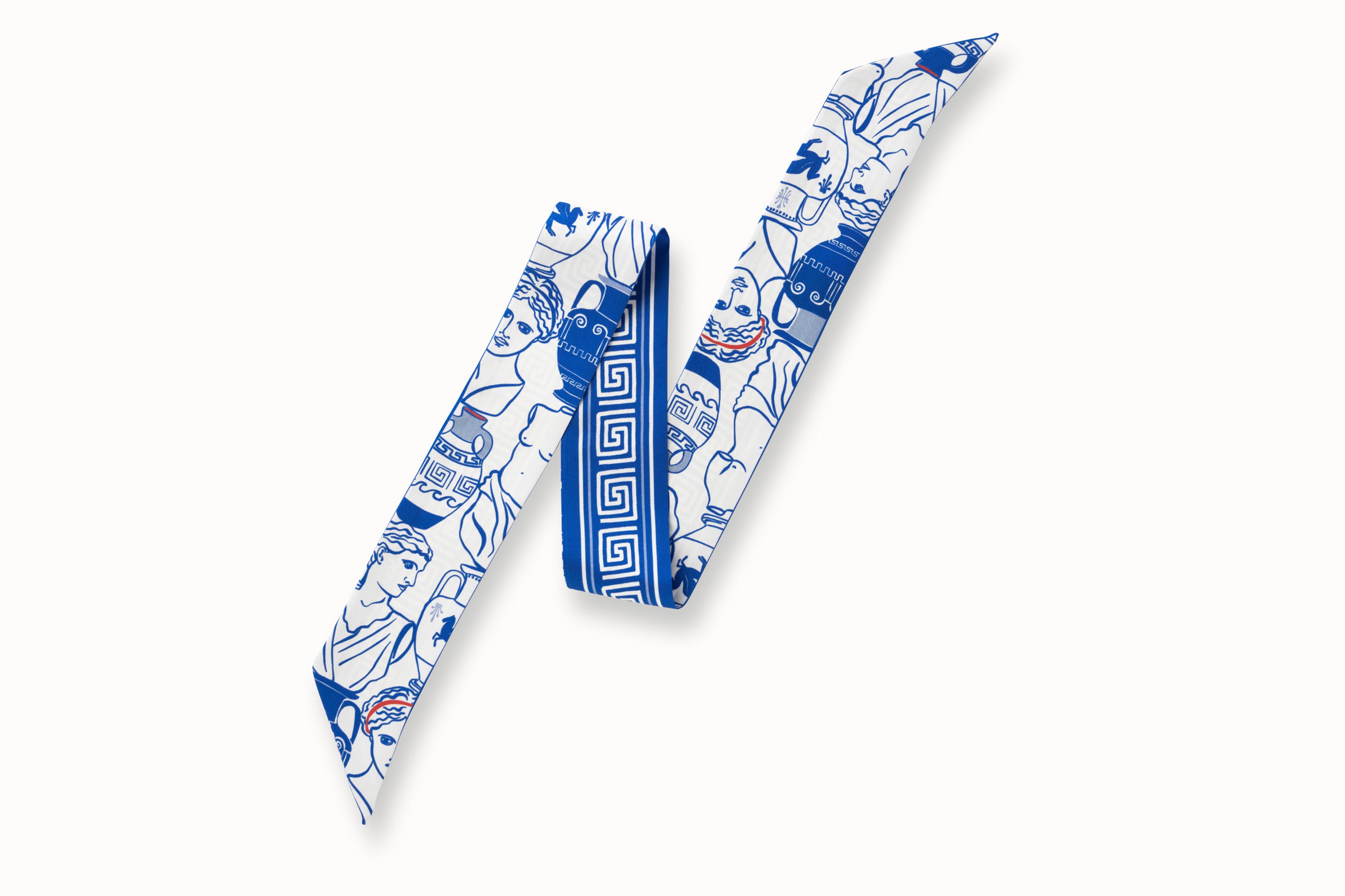 Flatlay image of 100% silk ribbon style scarf, 2” wide by 32” long, folded into a zig zag shape so both sides of the scarf are seen. Design features illustrations of Greek goddess busts and urns in a bright Aegean blue on a white background. The opposite side of the scarf features a white Greek key design motif on a bright blue background.