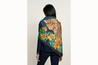 Image of a female model from behind wearing the scarf folded in half diagonally and draped across her shoulders where the leopard is predominantly featured. 