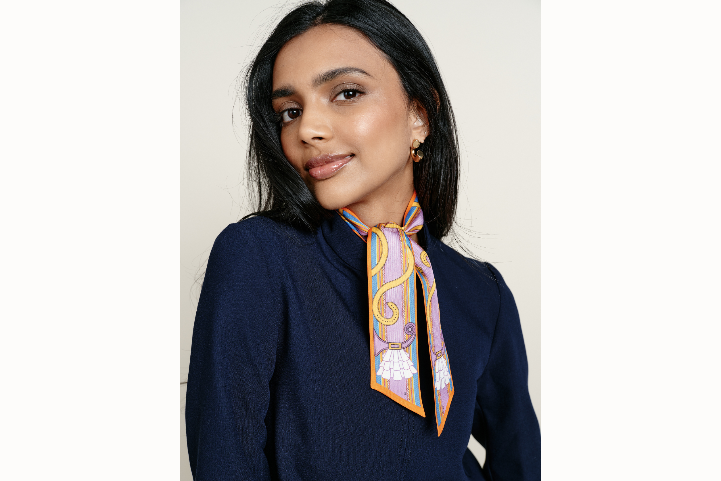 Image of a female model wearing the scarf wrapped around her neck with tail ends of the scarf draping onto her chest. Model is wearing a navy coord ensemble.