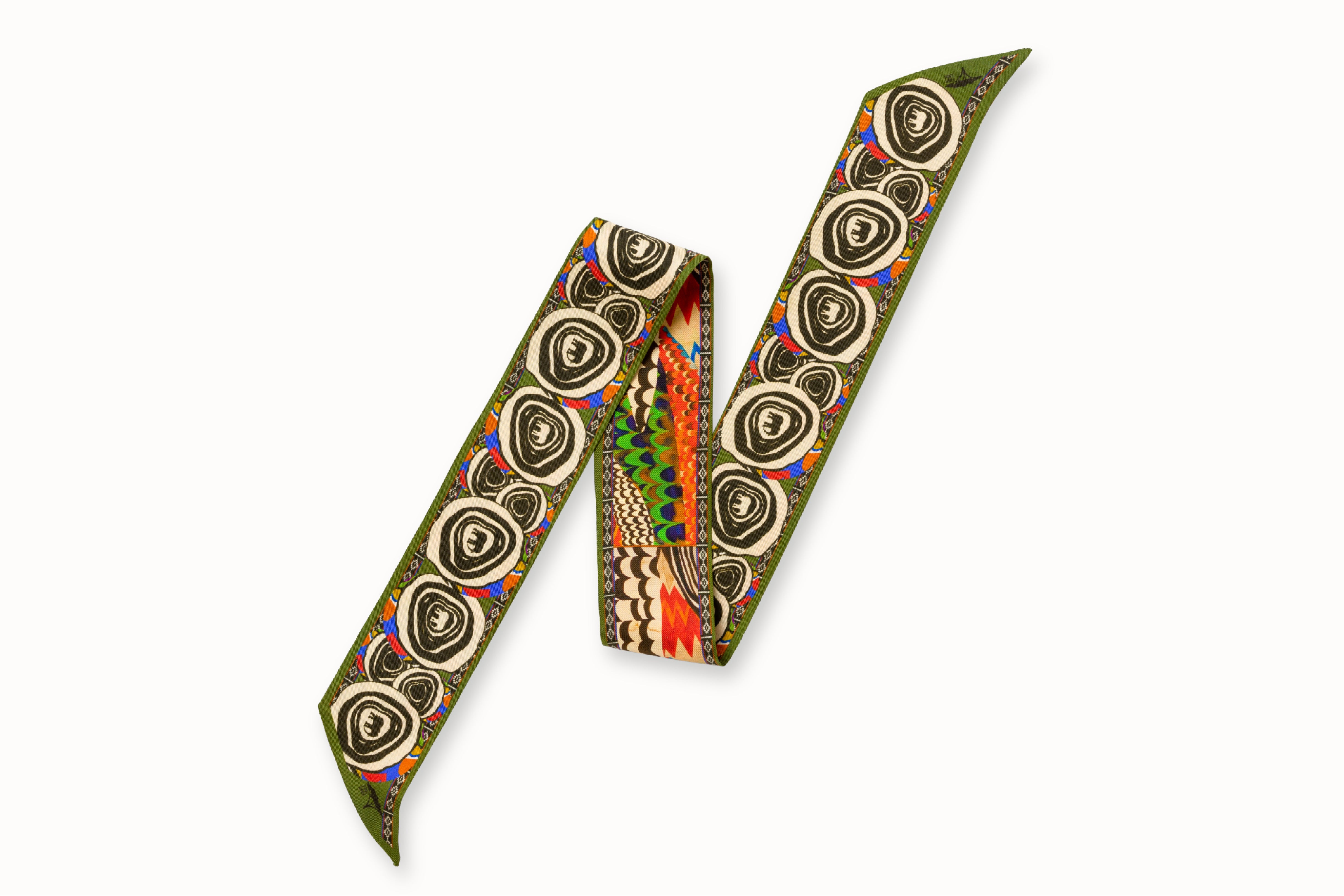 Flatlay image of 100% silk ribbon style scarf, 2” wide by 32” long folded into a zig-zag shape so both sides of the scarf are seen. Featuring an abstract elephant motif and a pattern inspired by a traditional African painting composed of orange, army green, and hints of blue. 