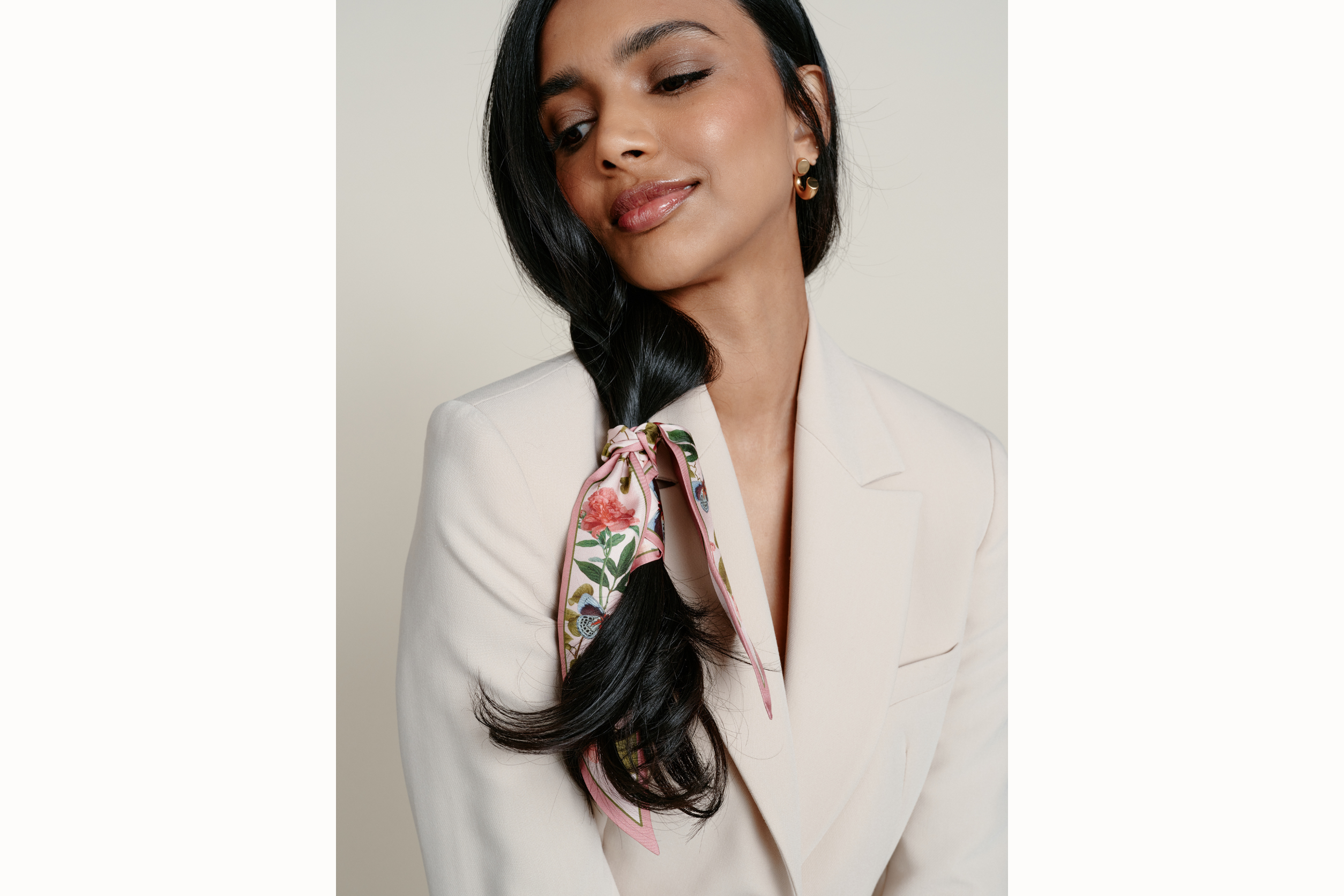 Image of female model wearing the scarf wrapped around her hair and tied in a simple knot. Model is wearing a neutral blazer. 