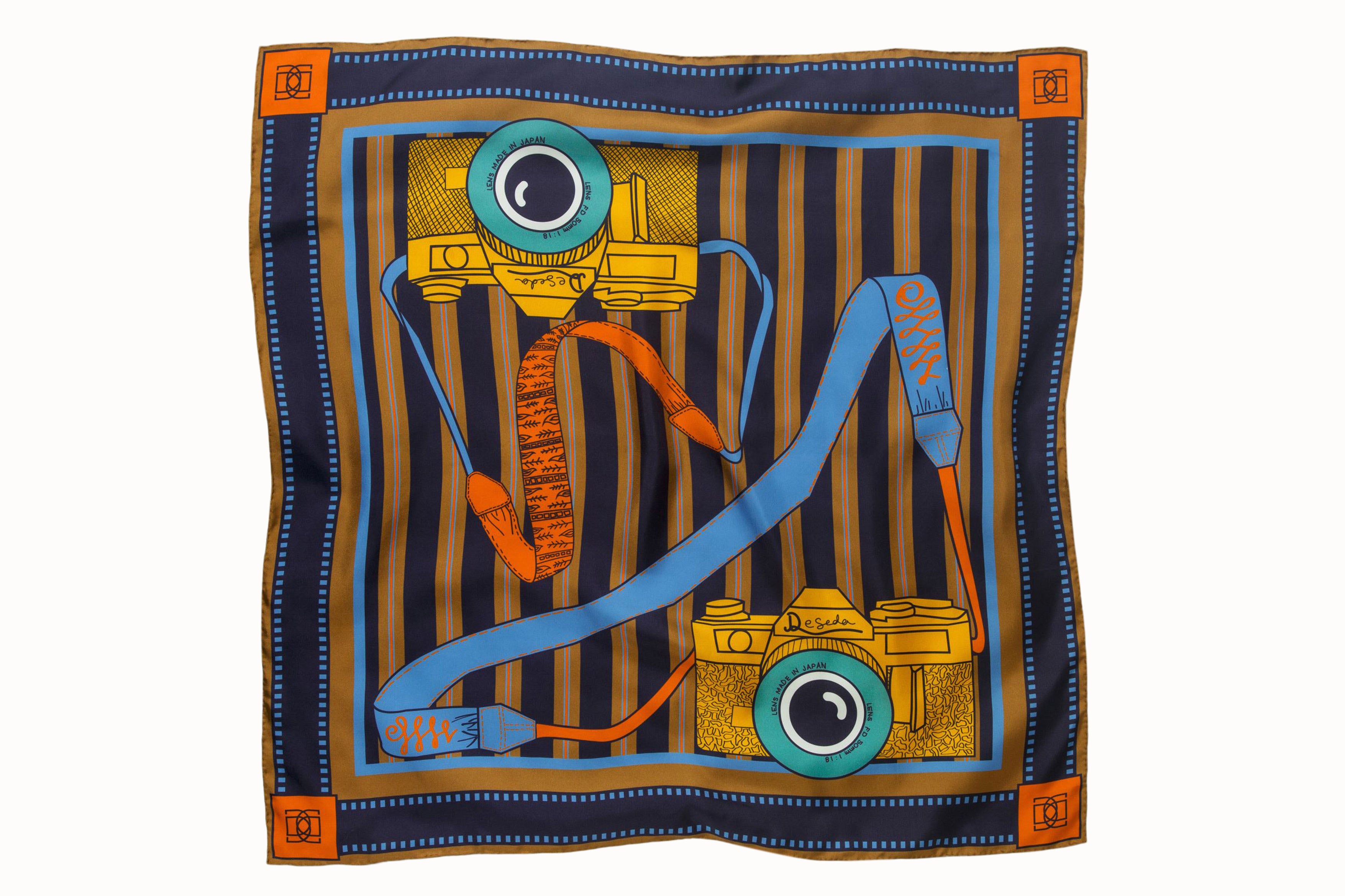 Flatlah image of 100% silk square scarf featuring a motif of two large-scale illustrated film cameras and their straps splashed on top of a multi-color striped background. Blue film-inspired border around scarf. Design features colors such as orange, navy, camel, maize and a touch of aqua.