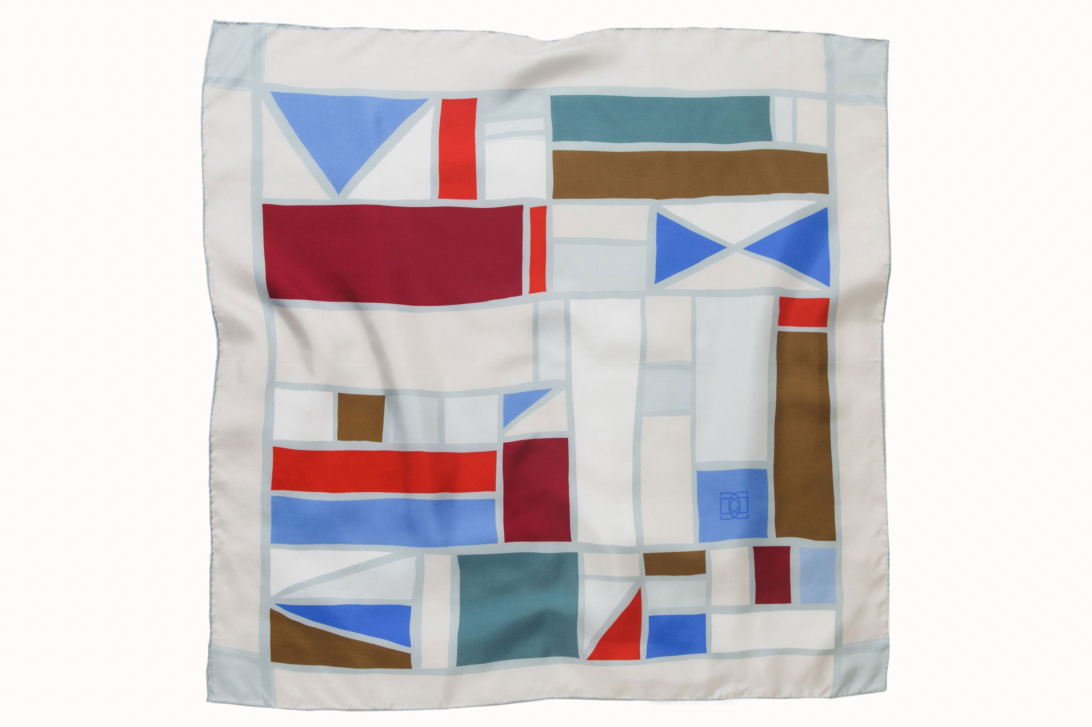 Flatlay image of 100% silk square scarf featuring a grouping of squares and rectangles of various sizes on an ecru background. Colors featured include crimson, cherry, khaki, cornflower blue and teal.
