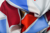 Close-up image of 100% silk square scarf featuring a grouping of squares and rectangles of various sizes on an ecru background. Colors featured include crimson, cherry, khaki, cornflower blue and teal. Illustrates the lightly ridged texture of the silk twill along with the rich color tones and luminous nature of the silk scarf.