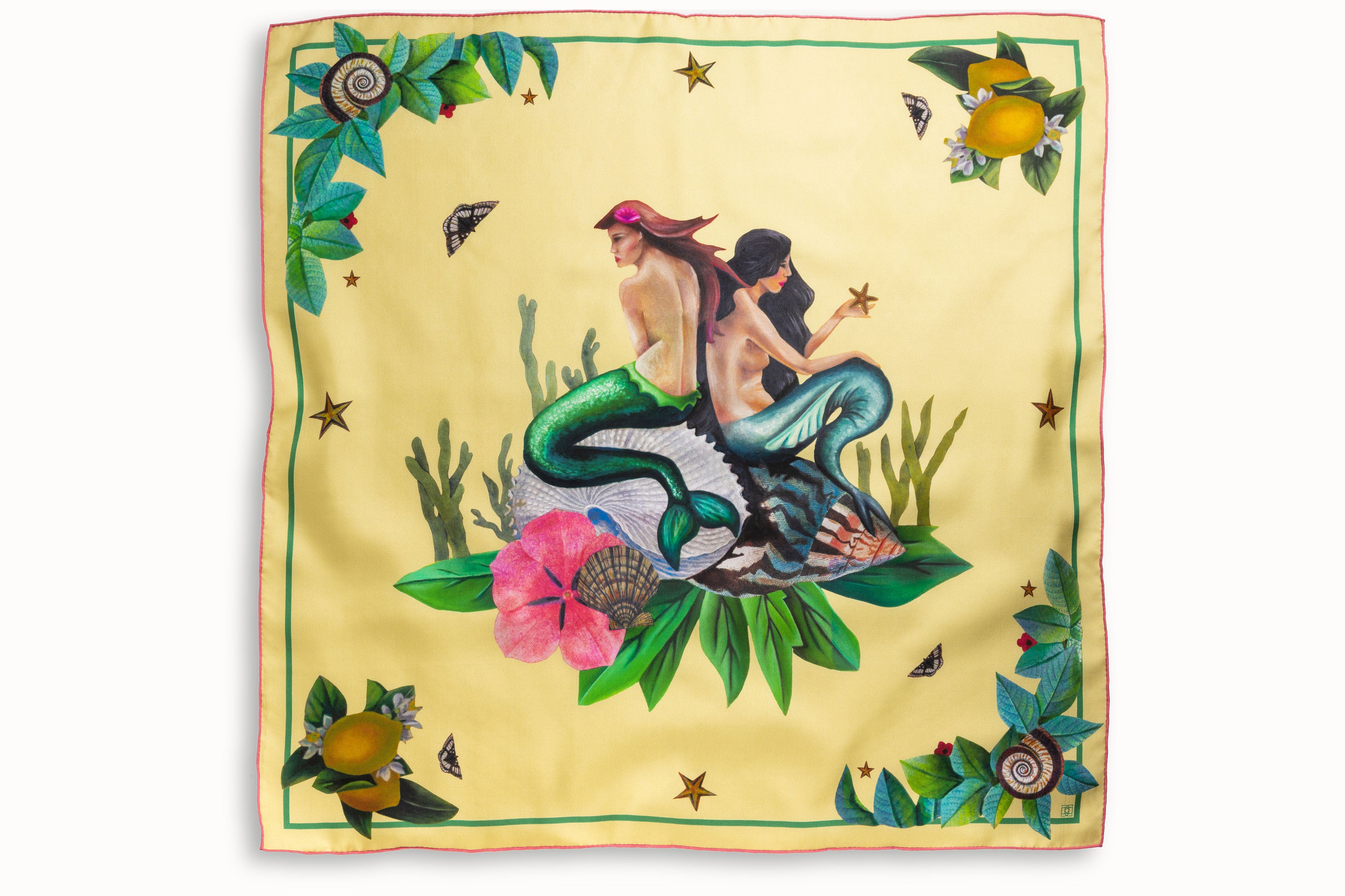 Flatlay image of 100% silk square scarf featuring two painted two mermaids resting on large sea shells, a pink flower and green seaweed on a lemon yellow background with small butterfly accents. Thin green border around the edges of the scarf, layered with green leaves, seashells and lemons.